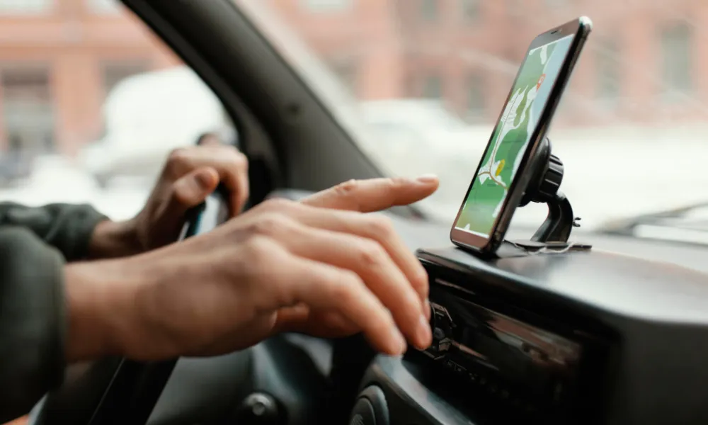 Conducteur utilisant son appareil fixé à un support de téléphone de voiture aimanté de design discret et élégant