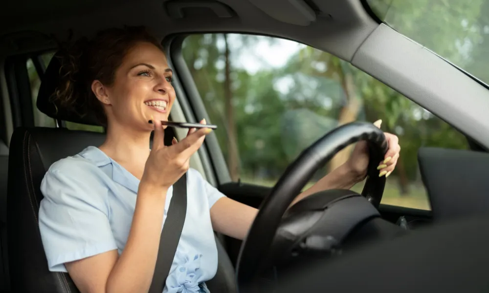 Les considérations légales pour votre support de téléphone dans votre voiture _ femme joyeuse qui parle au téléphone au volant