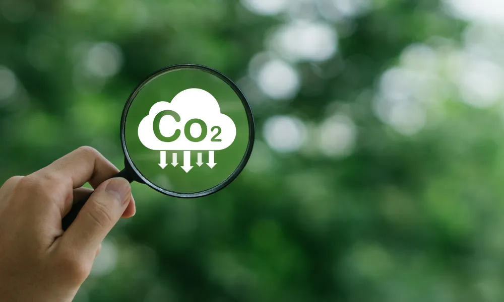 Main tenant une loupe pour visualiser les émissions de CO2